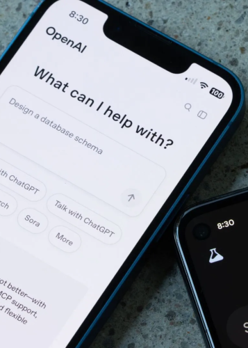 Közeli fotó egy okostelefon kijelzőjéről, amelyen az OpenAI ChatGPT alkalmazás "What can I help with?" kezdőképernyője látható. 
