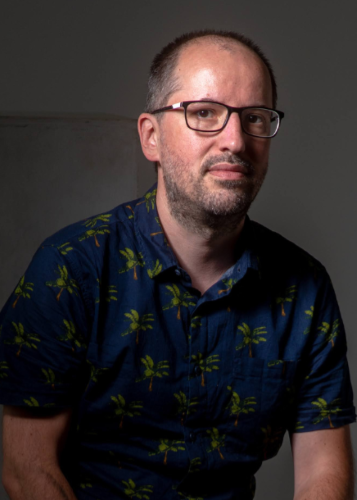 Portré egy szemüveges, pálmafás mintás inget viselő férfiról. Férfi, portré, szemüveg, divat, nyár, laza.