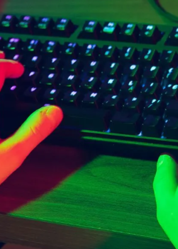 Kéz gépel egy megvilágított billentyűzeten élénk zöld és lila fényekben. Gamer, programozó, játék, kódolás, billentyűzet, éjszakai munka, technológia, digitális élet, online tevékenység.