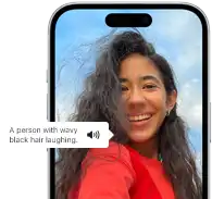 Az iPhone 15-ön a VoiceOver funkció épp elmondja, mi van egy képen: egy hullámos fekete hajú, nevető ember.